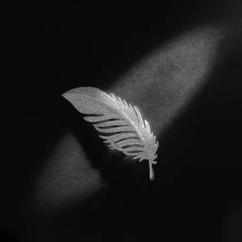Silver feather-shaped brooch on a dark background