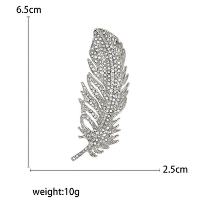 Feather-shaped brooch with gems and measurements and weight on a white background
