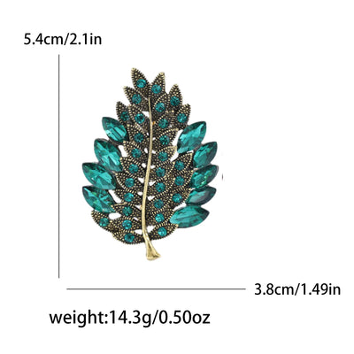 Leaf-shaped brooch with green gemstones and gold accents, shown with measurements and weight on a white background.