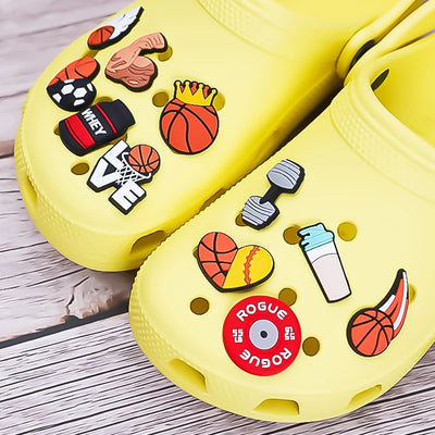 Yellow clogs with colorful decorative shoe charms on a wooden surface