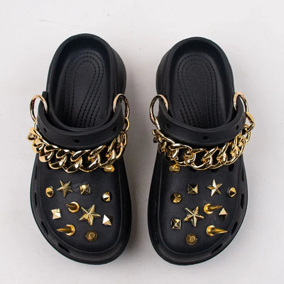 Black clogs with gold Rivet Shoe Charms and chains on a white background