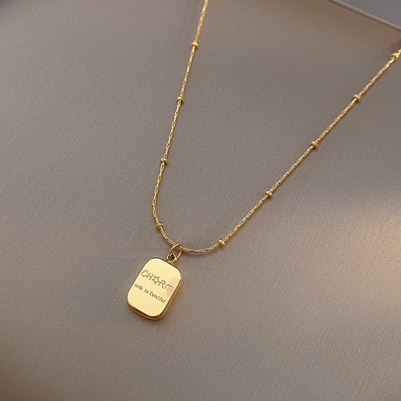 Gold necklace with a pendant on a gray background