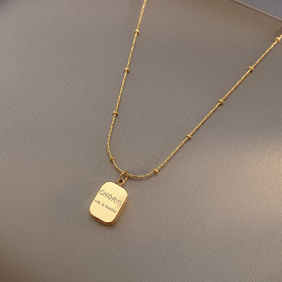 Gold necklace with a pendant on a gray background
