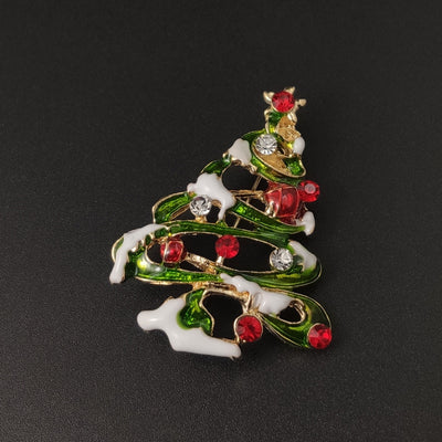 Christmas tree-shaped brooch with red berries and snow on a black background