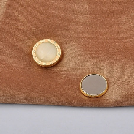Gold roman numbers magnetic brooch  and its magnet button on a brown fabric background