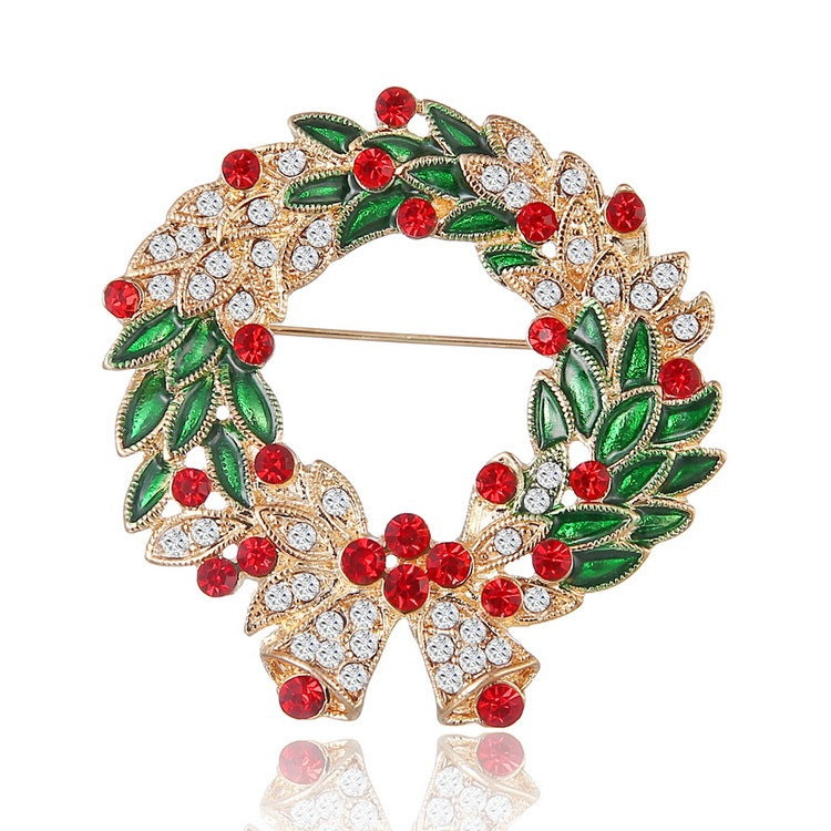 Decorative brooch with green leaves, red berries, and gold accents on a white background
