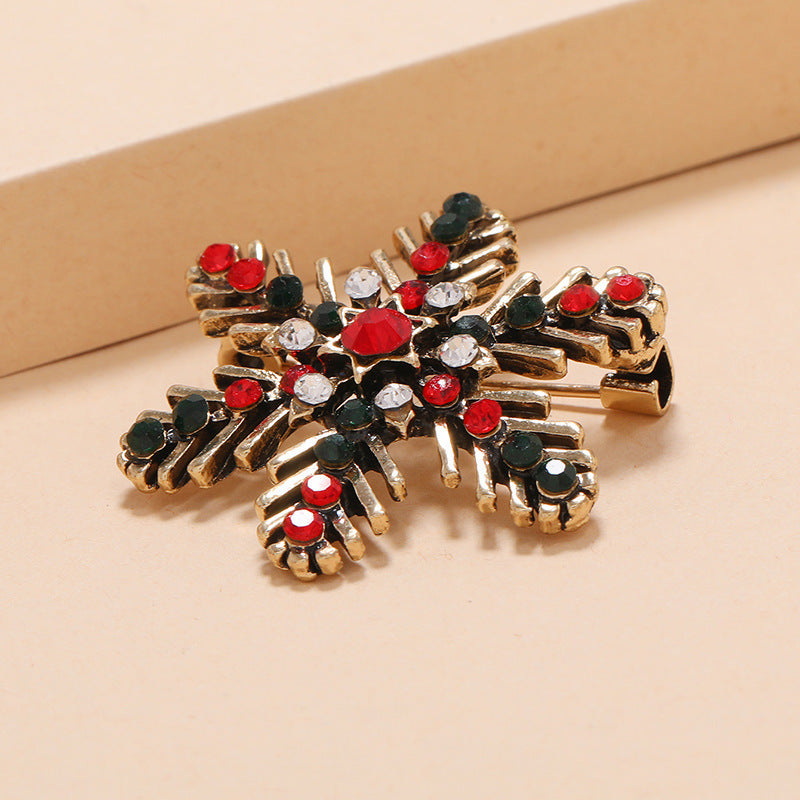 Gold brooch with red and black gemstones on a beige background