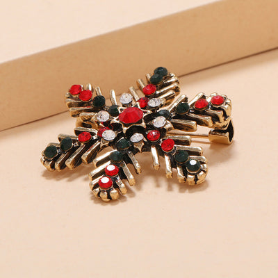 Gold brooch with red and black gemstones on a beige background