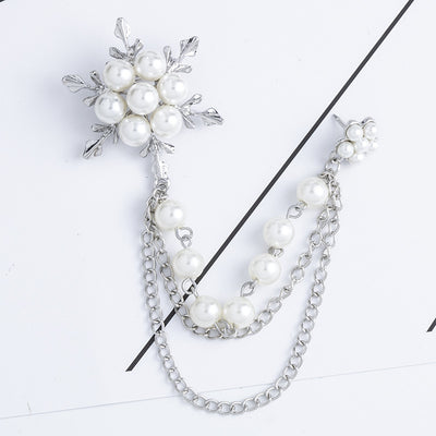 Pearl brooch with floral design and chain on a white background
