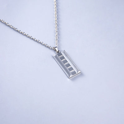 Silver necklace with a rectangular pendant on a light gray background