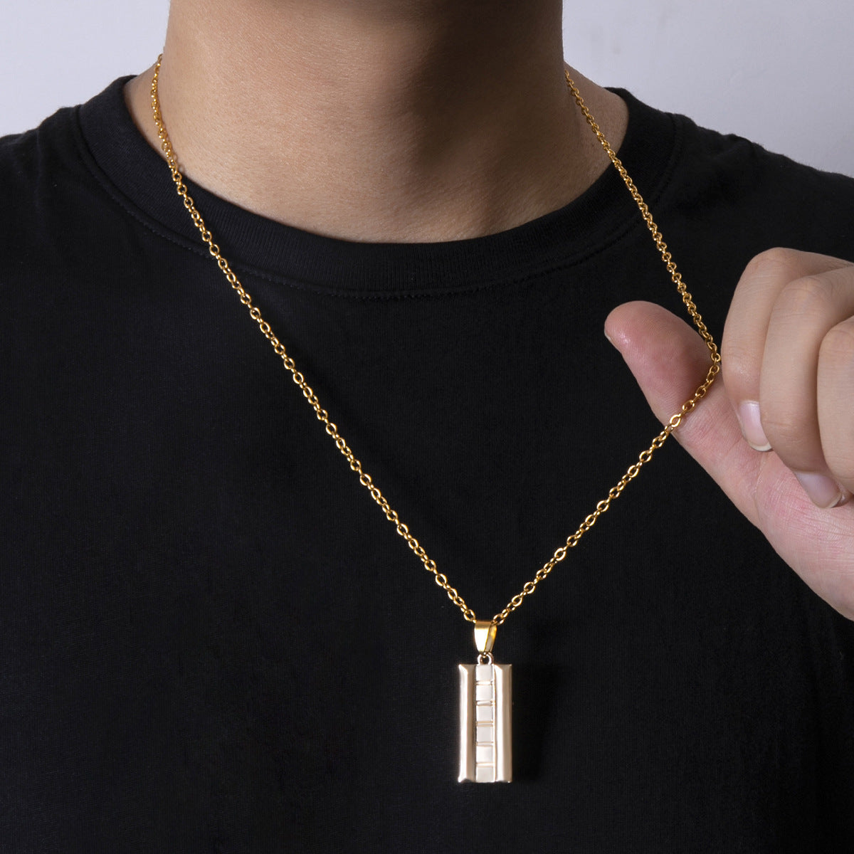Gold necklace with a pendant worn by a person against a black background