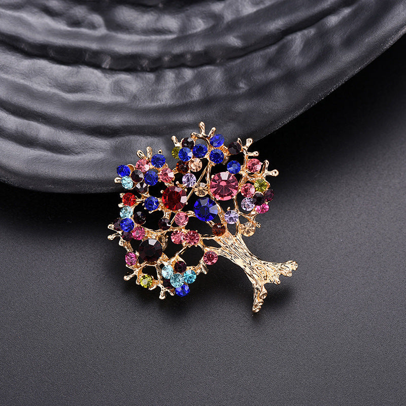 Colorful tree-shaped brooch with gemstones on a dark textured background