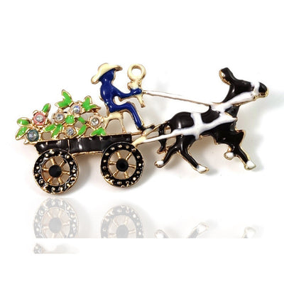 Brooch with a black and white dog pulling a cart with a man and flowers on a white background