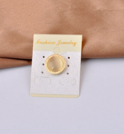 Gold roman numbers magnetic brooch and beige stone in Jewelry card on a beige fabric and white surface background 