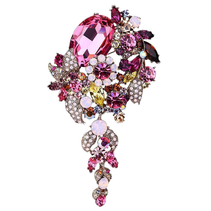 Multicolored jeweled brooch with pink gemstone on a white background