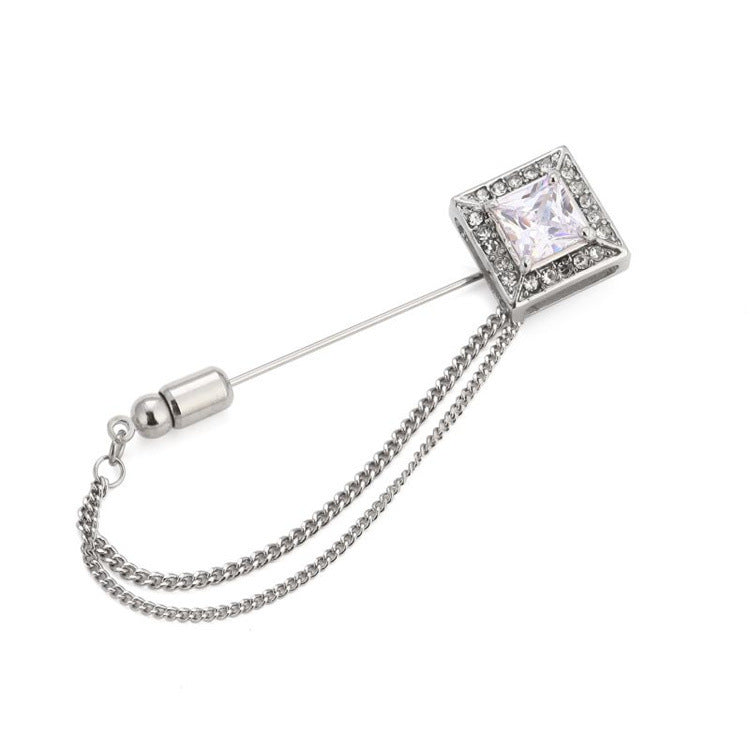 Silver brooch with a chain and clear gemstone on a white background