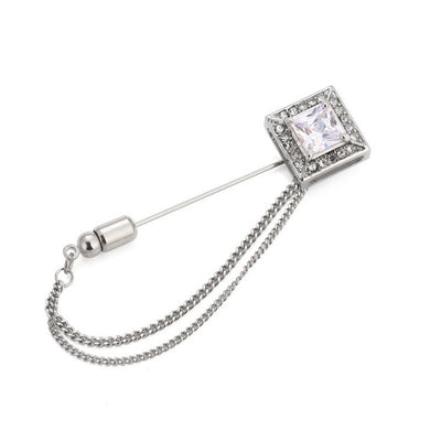 Silver brooch with a chain and clear gemstone on a white background