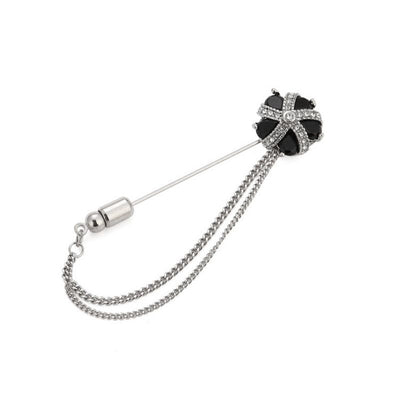 Black flower-shaped brooch with chain on a white background