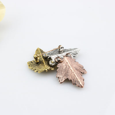 back side view of the Three metal leaf-shaped pins in gold, silver, and rose gold on a white background