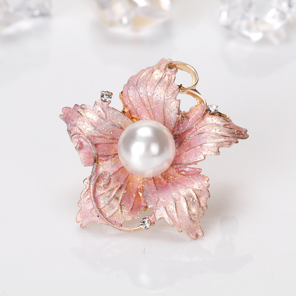 Pink leaf-shaped brooch with a pearl center on a light background