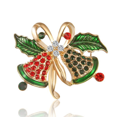 Decorative brooch with green leaves, red berries, and gold center on a white background