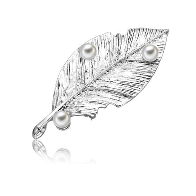 Silver leaf-shaped brooch with three pearls on a white background