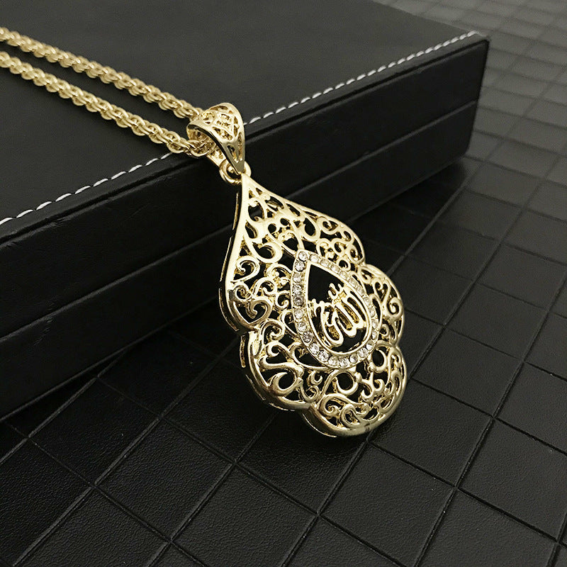A gold pendant with a delicate filigree design and sparkling rhinestones rests on a black textured surface, evoking elegance and luxury.