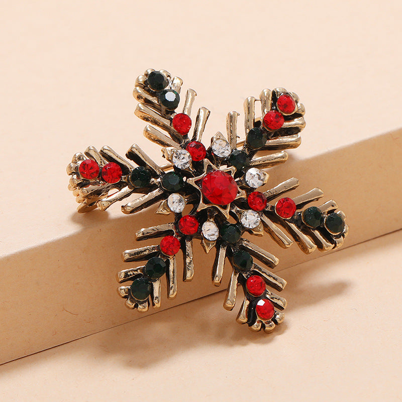 close up snowflake Christmas brooch   with red, black, and clear gemstones on a beige background