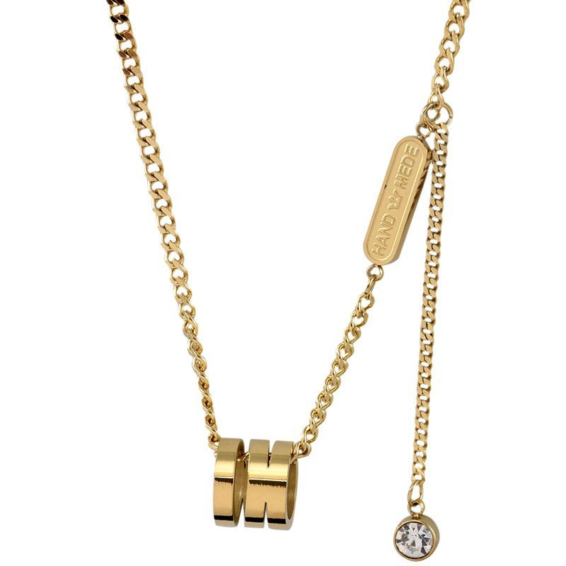 Gold tone  necklace with cylindrical pendants and a round pendant on a white background