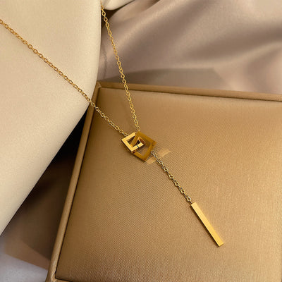 Gold necklace with a pendant on a beige surface