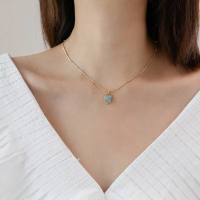 Necklace with a pendant worn by a person in a white top