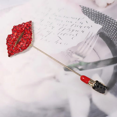 Red lip-shaped brooch with gemstones on a white surface