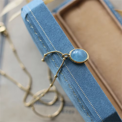 Gold bracelet with a blue gemstone on a blue stand