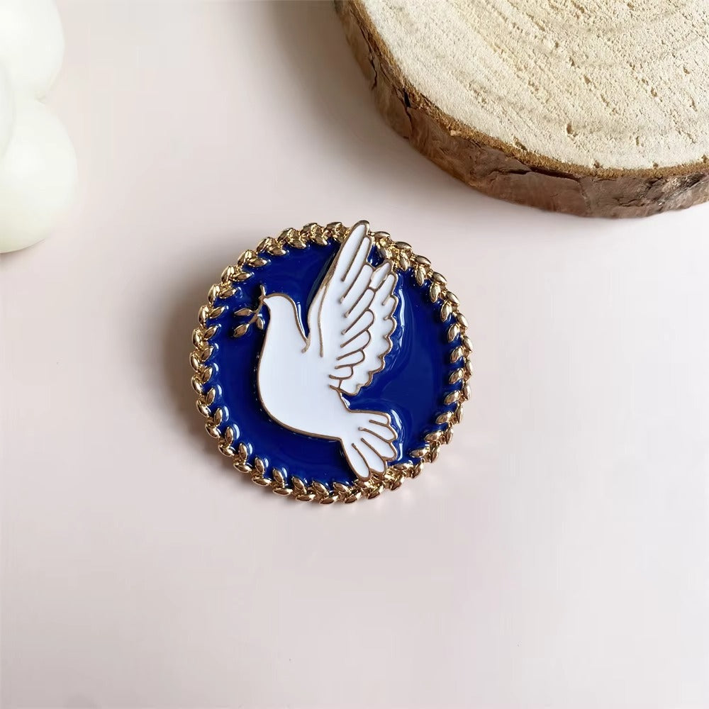 Pin with a dove design on a blue background, placed on a light surface.
