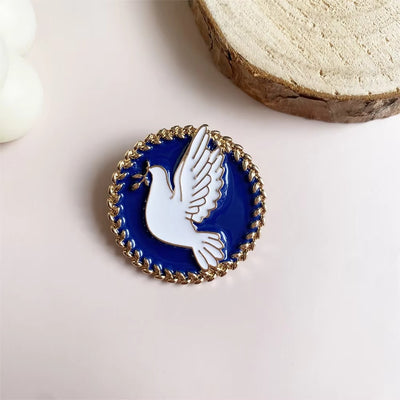 Pin with a dove design on a blue background, placed on a light surface.