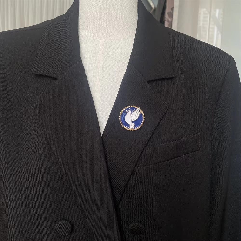 Black blazer with a blue and gold emblem on a mannequin against a neutral background