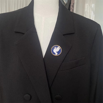 Black blazer with a blue and gold emblem on a mannequin against a neutral background