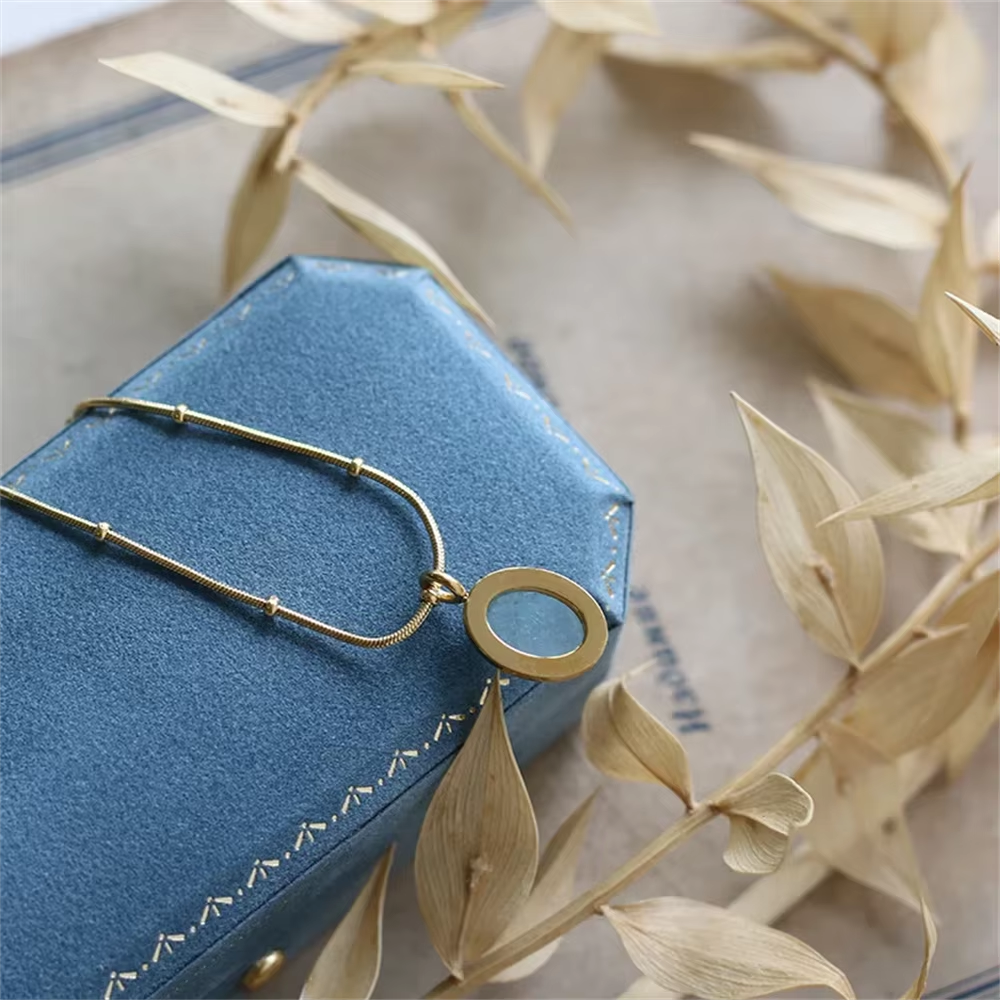 Back side of Gold necklace on a blue jewelry box with dried leaves