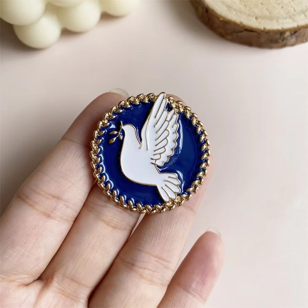 Pin with a dove design held between fingers on a light background