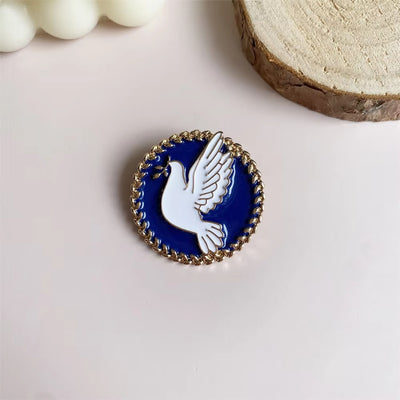 Pin with a white dove on a blue background, set against a light pink surface with decorative elements.