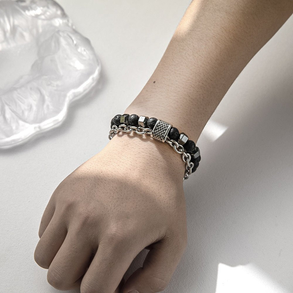 Hand wearing a black beaded bracelet on a light background
