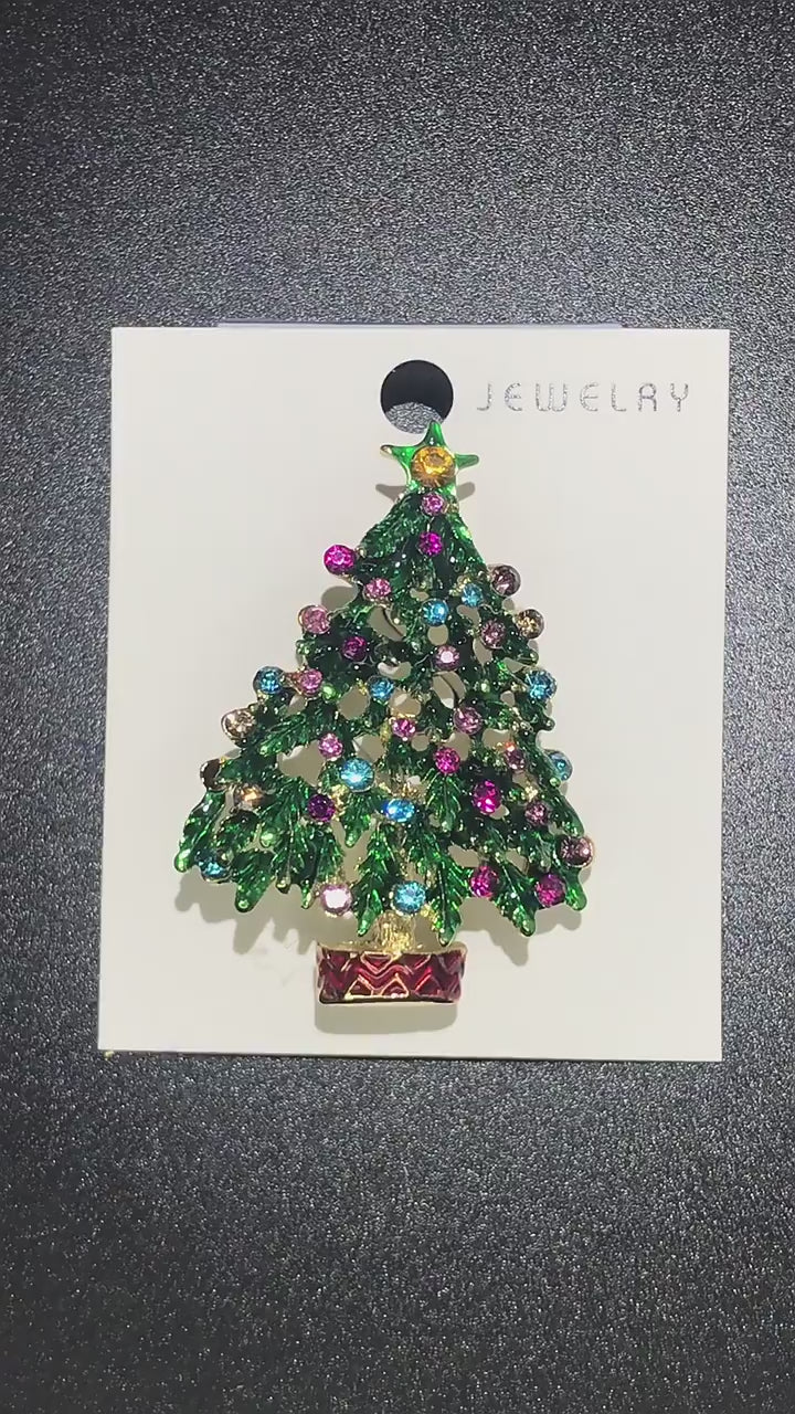 video showing Decorative brooch shaped like a Christmas tree with colorful gemstones on a jewelry cart
