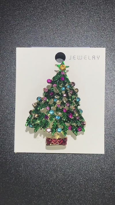 video showing Decorative brooch shaped like a Christmas tree with colorful gemstones on a jewelry cart