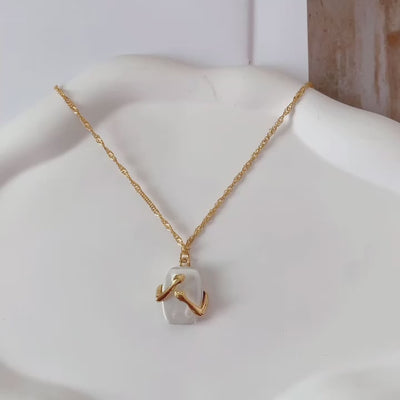 video of a Gold necklace with a hands hugging a white Natural iridescent stone pendant on a white Dish and on a hand 