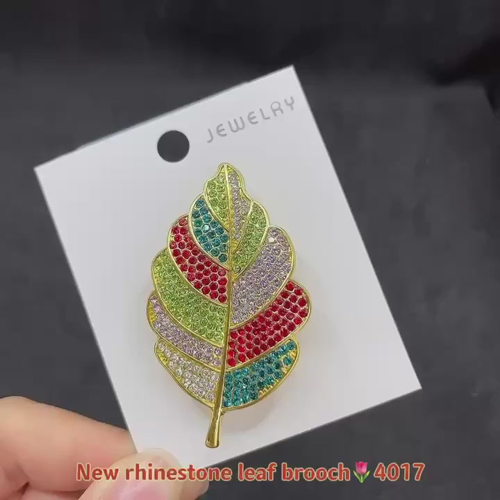 video of a Colorful feather-shaped brooch on a jewelry cart and then hand on a dark background