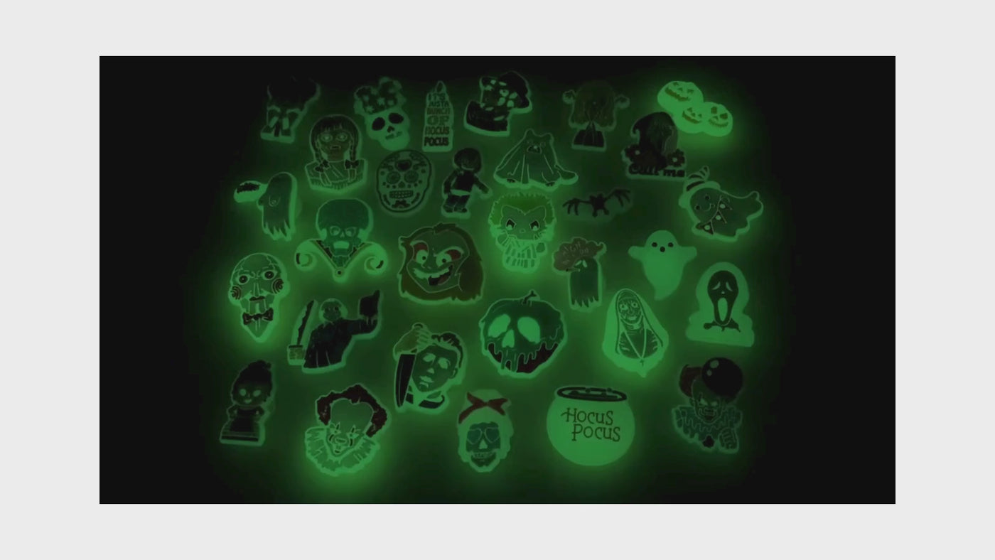 video of an Assorted green glow-in-the-dark shoe charms on a black background
