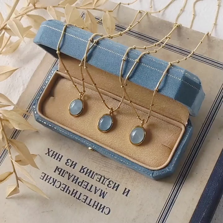 Video of Gold tone necklace with blue stones on a jewelry display box and on hand