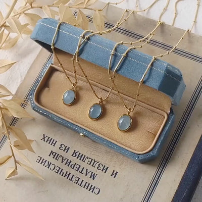 Video of Gold tone necklace with blue stones on a jewelry display box and on hand